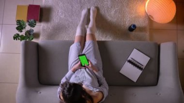 Genç çekici kadın genç closeup üst ateş yeşil renk ekranı ile telefonda sohbet sevimli çorap kapalı kanepede oturan