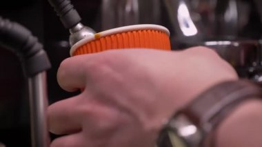Kapalı bir kafede üç bölmeli lavabo kullanarak karton bardağa dökülen bolied su Closeup ateş