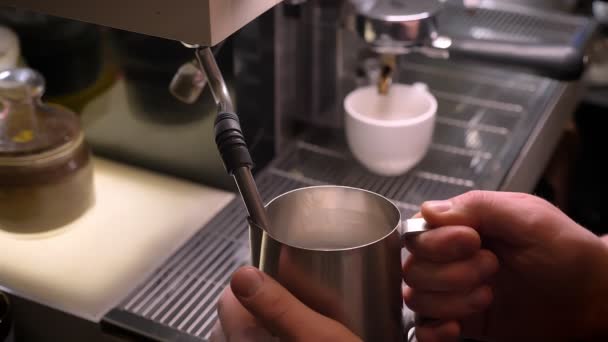 Gros plan tige de barista mains lait bouillant dans pichet en argent à l'aide de l'évier à trois compartiments dans un café à l'intérieur — Video