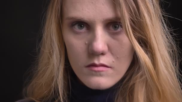 Close-up portret van jonge blonde model met fuzz haar kijken ellendelijk in de camera op zwarte achtergrond. — Stockvideo