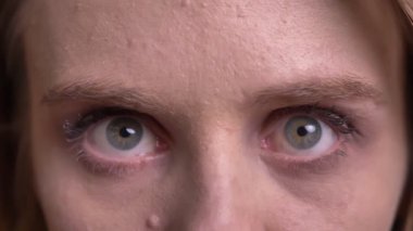 Siyah arka plan da kameraya özenle ve sabit bir şekilde izleyen sevimli sarışın modelin yakın çekim göz portresi.