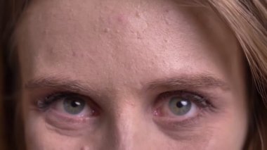 Siyah arka plan üzerinde utangaç ve güzel bir gülümseme ile kameraya izlerken genç sarışın modelin Göz portresi.