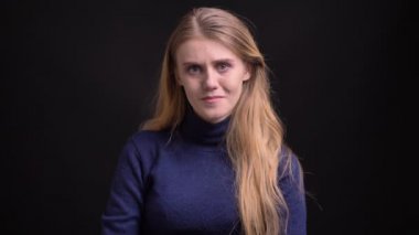 Siyah arka planda ağlamaya hazır olan kameraya dikkatlice izlerken tüylü saçlı genç sarışın modelin portresi.