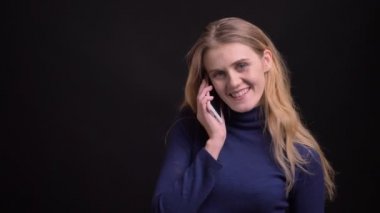 Sarışın model siyah arka plan üzerinde kameraya gülümseyerek izlerken akıllı telefonda hoş bir voicecall sahip.