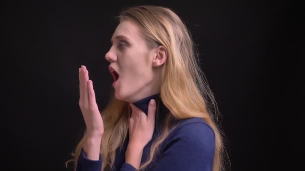 Porträt eines traurigen jungen blonden Models mit Wuschelhaaren, das an Grippe leidet und auf schwarzem Hintergrund hustet. — Stockvideo