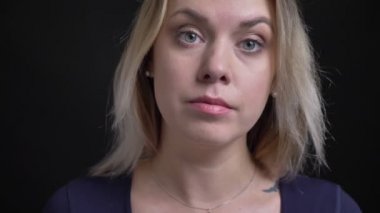 Siyah arka planda kameraya meraklı izlerken kepçe yaka ile mavi bluz orta yaşlı sarışın iş kadını yakın çekim.