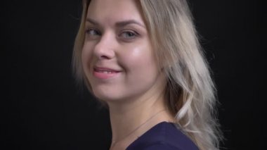 Mavi bluzlu mutlu orta yaşlı sarışın iş kadını kameraya döner ve siyah arka planda içine sevinçle saatler.