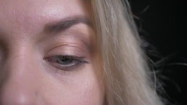 Orta yaşlı sarışın iş kadınının yakın çekim yarım yüz siyah arka planda kameraya ciddi bir şekilde saatler.