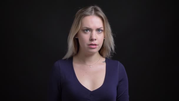 Medelålders blondin affärskvinna i blå blus med Scoop urringning tittar aggressivt i kameran på svart bakgrund. — Stockvideo
