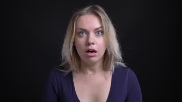 Middle-aged blonde businesswoman in blue blouse gets surprised and shocked on black background. — Stock Video