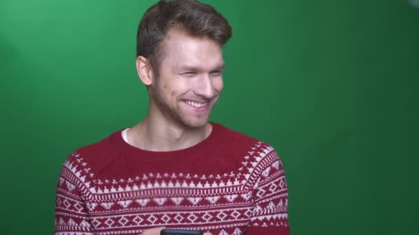 Happy young brunette businessman working with cellphone and smiling into camera on green background. — Stock Video