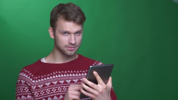 Gelukkig jonge brunette zakenman draait op de app en toont blauw scherm van Tablet op groene achtergrond. — Stockvideo