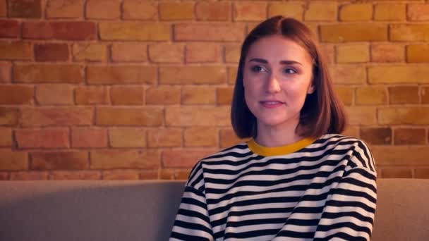 Gros plan portrait de jeune jolie fille regarder une comédie à la télévision rire heureux assis sur le canapé étant détendu dans un appartement confortable à l'intérieur — Video