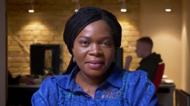 Kamera bakarak ve ofiste kapalı mutlu gülümseyen yetişkin Afro-Amerikan iş kadını Closeup ateş