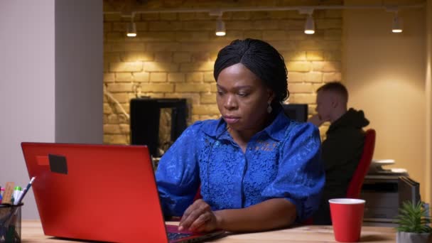忙碌的非洲裔美国员工使用笔记本电脑在办公室室内喝咖啡的特写镜头 — 图库视频影像