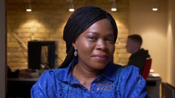 Nahaufnahme einer erfolgreichen erwachsenen afrikanisch-amerikanischen Geschäftsfrau, die in die Kamera blickt und im Büro drinnen glücklich lächelt — Stockvideo