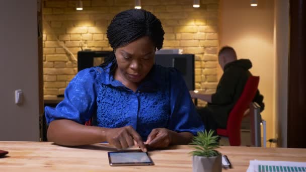 Gros plan shoot of adult african american businesswoman texting on the tablet in the office à l'intérieur sur le lieu de travail — Video