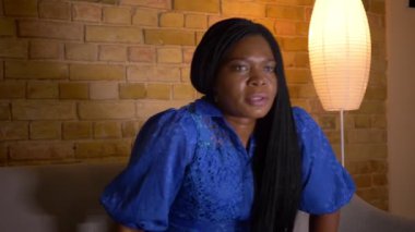 Tv'de spor izleyen ve kapalı kanepede oturan kayıp nedeniyle hayal kırıklığına uğrayan yetişkin Afro-Amerikan kadın Closeup ateş