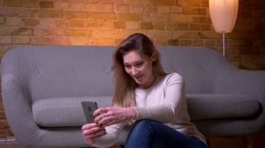 Rahat bir dairede kapalı yerde oturarak telefon kullanarak genç çekici kafkas esmer kadın Closeup portre