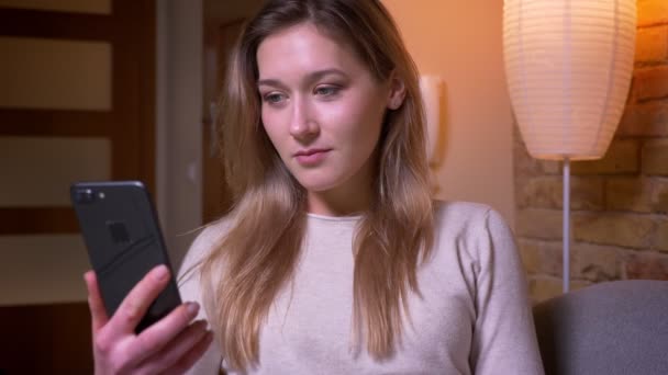 Closeup portrait of young attractive caucasian brunette female using the phone and showing green chroma screen to camera indoors in a cozy flat — Stock Video