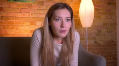 Tv'de bir korku filmi izlerken ve rahat bir dairede kanepede oturarak korkmuş ve şok olmak genç çekici kafkas esmer kadın Closeup portre