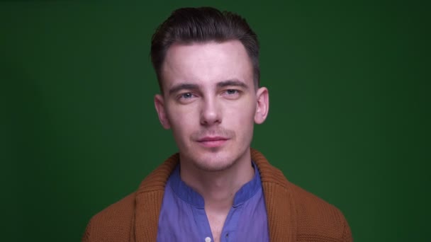 Close-up shoot van volwassen aantrekkelijke man kijken naar camera met achtergrond geïsoleerd op groen — Stockvideo