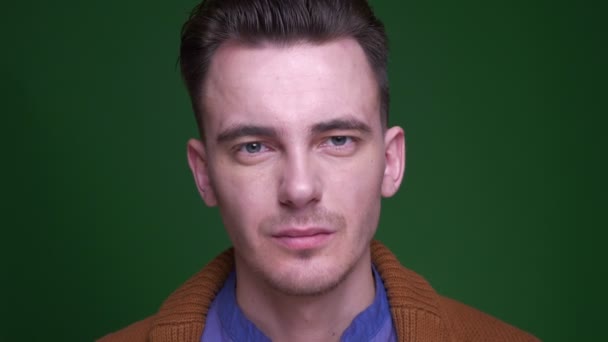 Närbild shoot of Adult attraktiva manliga ansikte tittar på kameran witrh koncentration med bakgrund isolerad på grön — Stockvideo