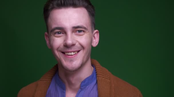 Close-up shoot van volwassen aantrekkelijke man wordt opgewonden en verrast kijkend naar camera met achtergrond geïsoleerd op groen — Stockvideo