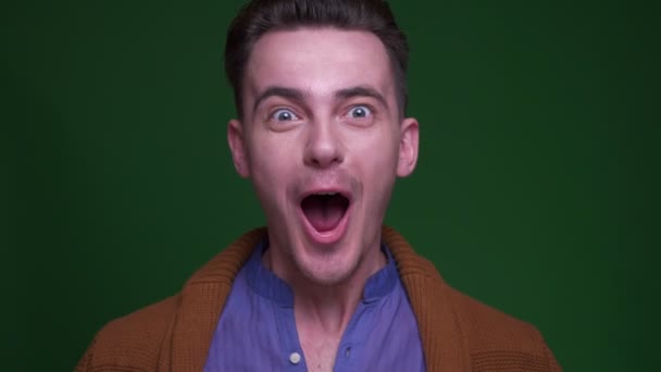 Closeup shoot of adult attractive man being excited and screaming happily looking at camera with background isolated on green — Stock Video