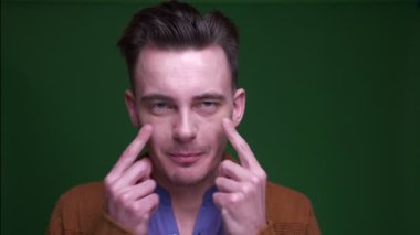 Yetişkin çekici adam komik yüz ifadeleri yapma ve yeşil izole arka plan ile kamera bakarak eğlenmek Closeup ateş