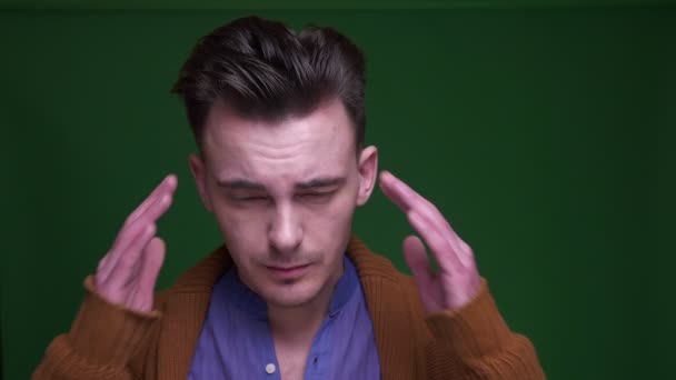 Primer plano de brote de hombre atractivo adulto que tiene un dolor de cabeza y estar cansado con fondo aislado en verde — Vídeo de stock