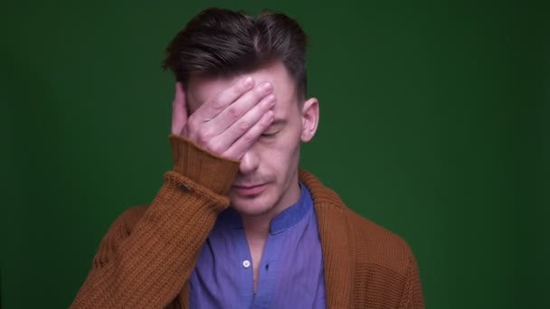 Closeup shoot of adult attractive man being annoyed and clapping his head with a hand looking at camera with background isolated on green — Stock Video