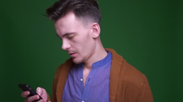 Closeup shoot of adult attractive man using the phone with background isolated on green — Stock Video