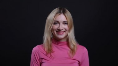 Pembe bir kazak genç güzel sarışın kadın Closeup ateş gülümseyerek ve siyah izole arka plan ile kamera bakarak sevimli olmak