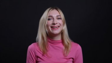 Siyah izole arka plan ile kamera bakarak mutlu bir şekilde gülen genç güzel sarışın kadın Closeup ateş