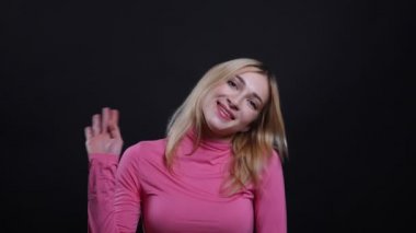 Merhaba sallayarak genç güzel sarışın kadın Closeup ateş ve mutlu siyah izole arka plan ile kamera bakarak gülümseyerek