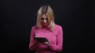 Siyah izole arka plan ile kamera önünde tablet kullanarak genç güzel sarışın kadın Closeup ateş