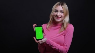 Telefonu kullanarak ve siyah izole arka plan ile kameraya uygulama ile yeşil ekran gösteren genç güzel sarışın kadın Closeup ateş