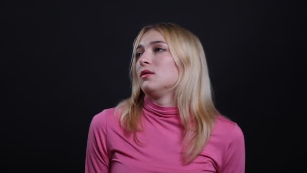 Close-up shoot van jonge mooie blonde vrouw die verdrietig en teleurgesteld is kijkend naar camera met achtergrond geïsoleerd op zwart — Stockvideo