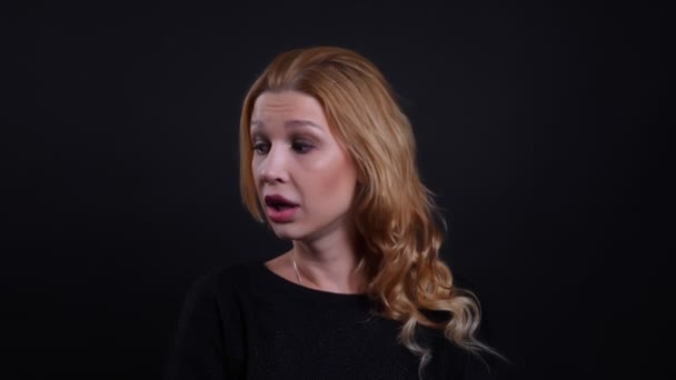 Closeup portrait of adult attractive redhead female being bored and annoyed looking at camera with background isolated on black — Stock Video