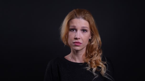 Closeup portrait of adult attractive redhead female being sad and disappointed looking at camera with background isolated on black — Stock Video