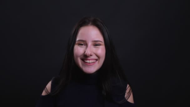 Nahaufnahme Porträt der jungen attraktiven brünetten Frau lächelt und lacht glücklich in die Kamera mit Hintergrund isoliert auf schwarz — Stockvideo