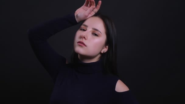 Closeup portrait of young attractive brunette female model smiling seductively and looking at camera with background isolated on black — Stock Video