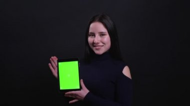 Tablet kullanarak genç çekici esmer kadın Closeup portre ve siyah izole arka plan ile kameraya yeşil ekran gösteren