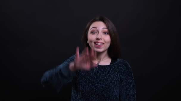 Closeup portrait of adult beautiful caucasian brunette female waving hi with her hand looking at camera with background isolated on black — Stock Video