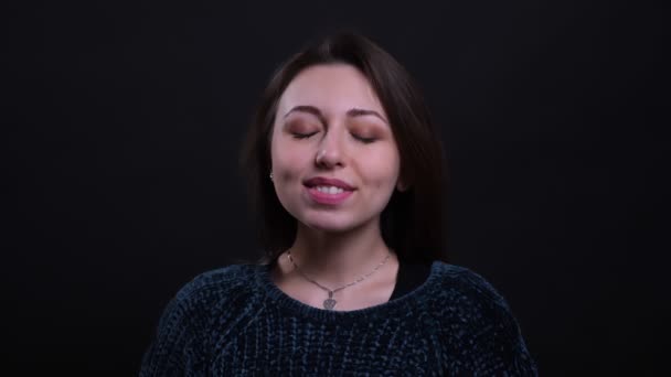 Closeup retrato de adulto bela morena caucasiana fêmea sorrindo com alegria e satisfação com os olhos fechados na frente da câmera com fundo isolado em preto — Vídeo de Stock