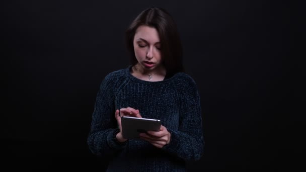 Gros plan portrait d'adulte belle brune caucasienne texte féminin sur la tablette avec fond isolé sur noir — Video