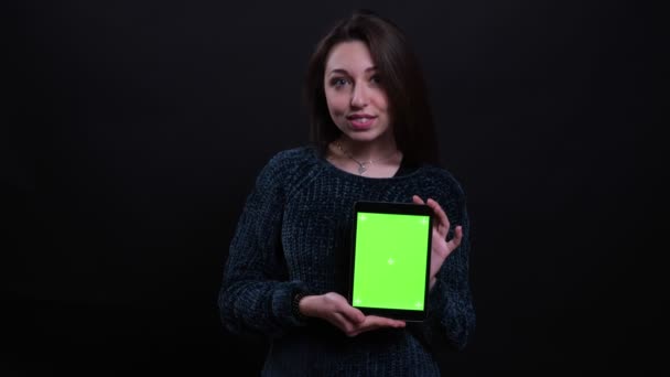 Closeup portrét dospělé krásné kavkazské bruneté ženy používající tablet a zobrazující zelenou obrazovku Chroma s klíčem na kameru s pozadím izolovaným na černém — Stock video