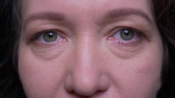 Closeup portrait of old caucasian brunette female face with eyes looking at camera with smiling facial expression with background isolated on green — Stock Video