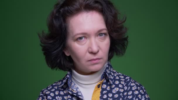 緑の上に隔離された背景を持つカメラを見て不賛成を示していないと言って彼女の頭を振る古い白人ブルネットの女性のクローズアップ肖像画 — ストック動画